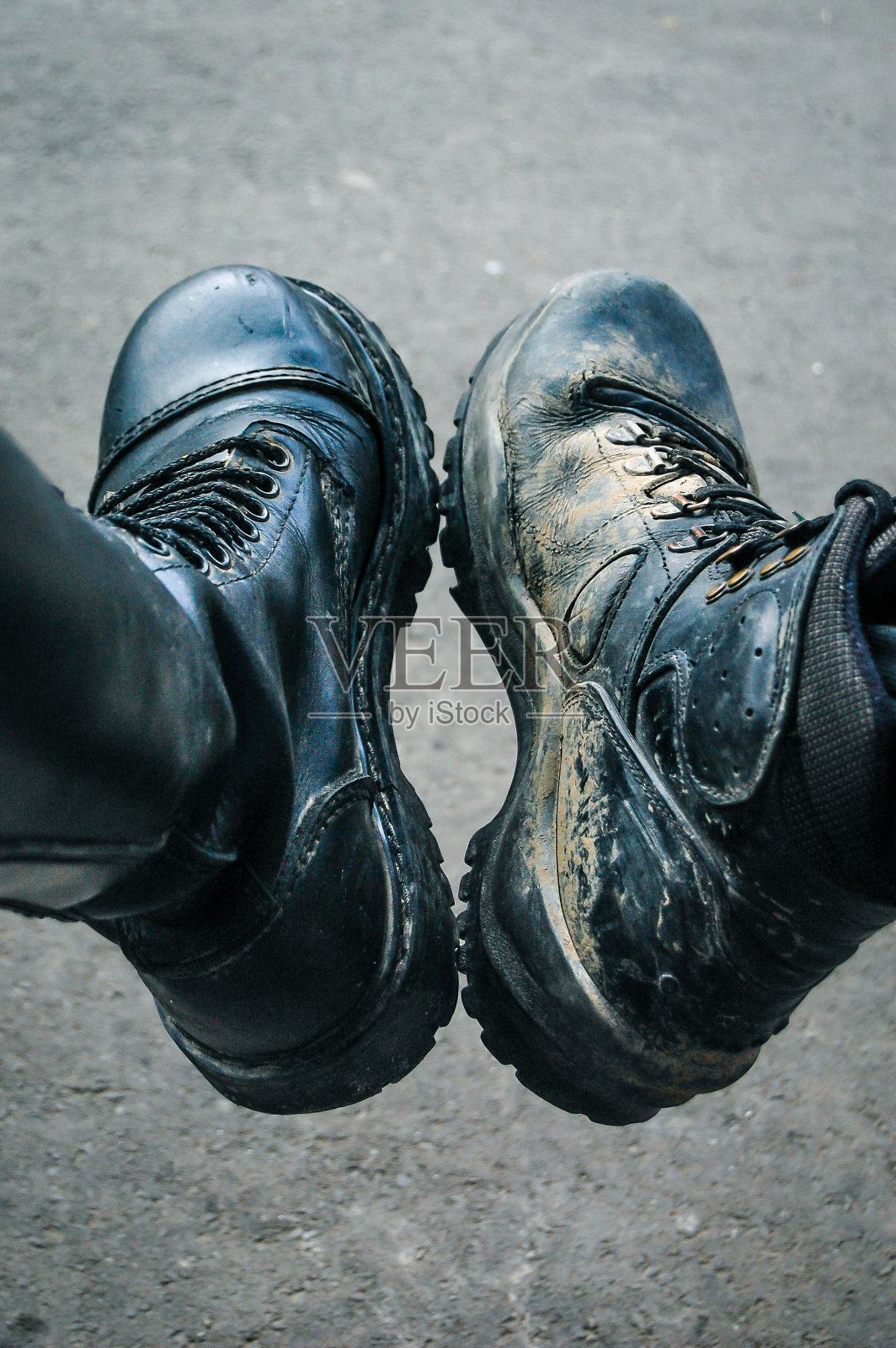 两个黑色的靴子。一双沾满泥巴的靴子并排放在一个男人和一个女人身上。照片摄影图片