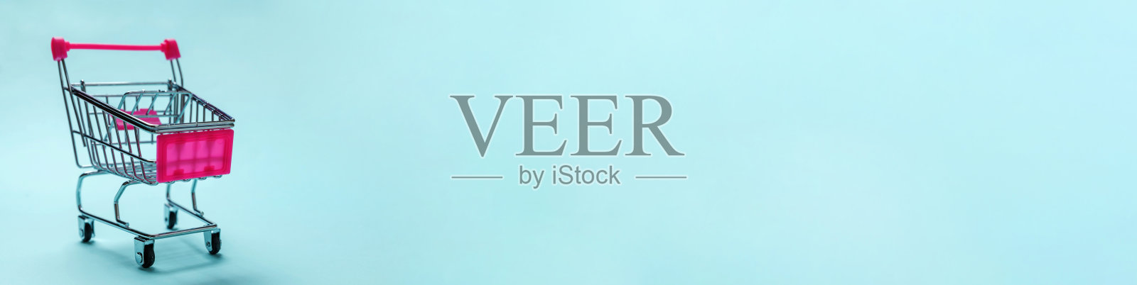 简单的最小设计与小型超市杂货店推车购物玩具车轮孤立在蓝色柔和背景。销售购买商场市场商店消费者的概念。复制空间,横幅照片摄影图片