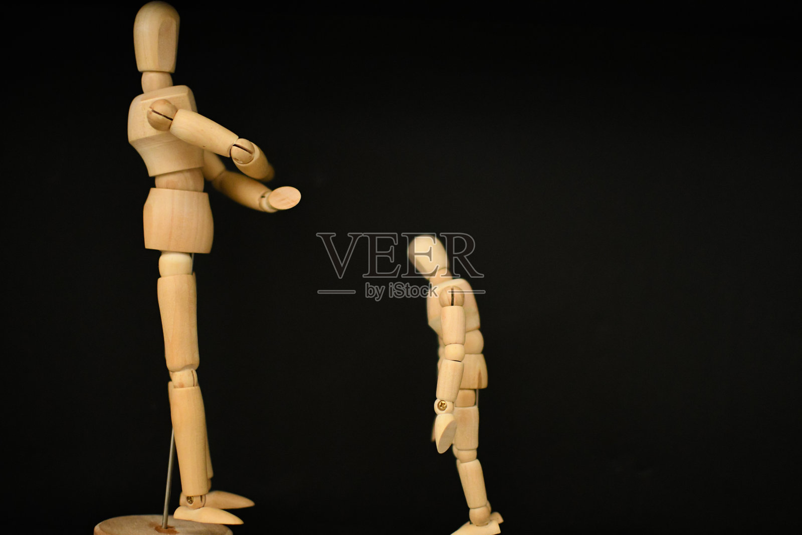 木制人体模型坐在黑色背景的男人和一个小照片摄影图片