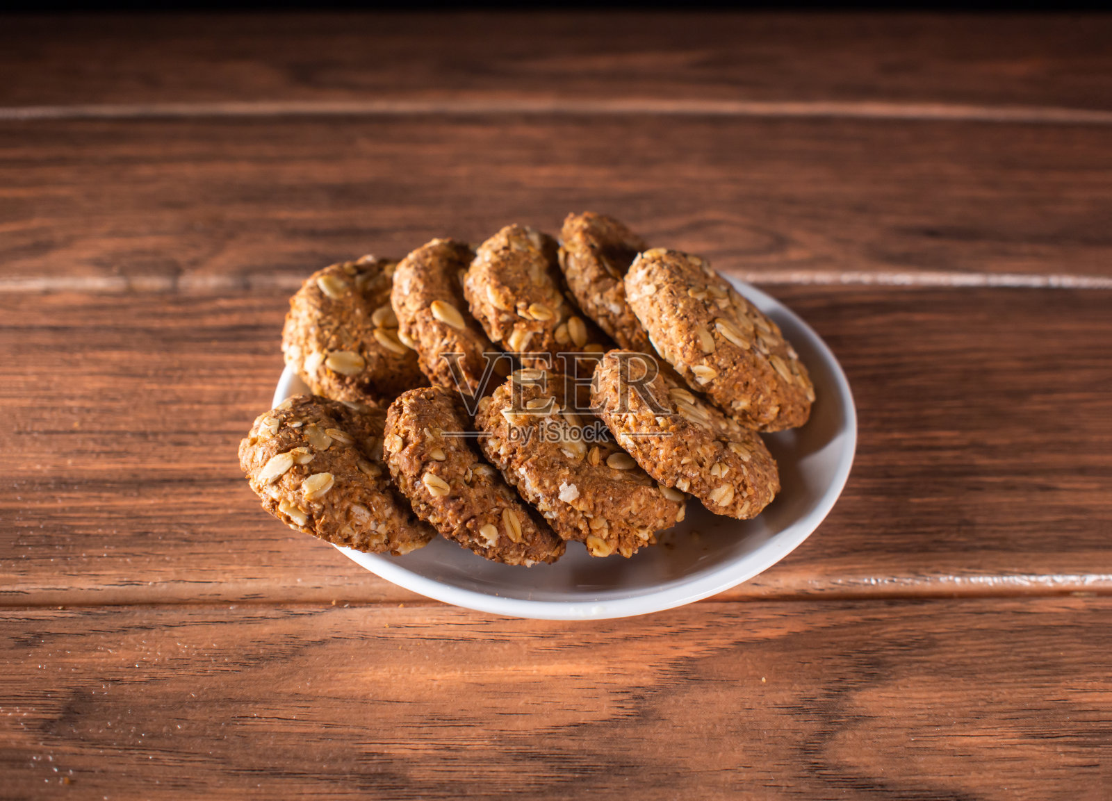 自制燕麦饼干在一个白色陶瓷盘子上的木头特写镜头照片摄影图片