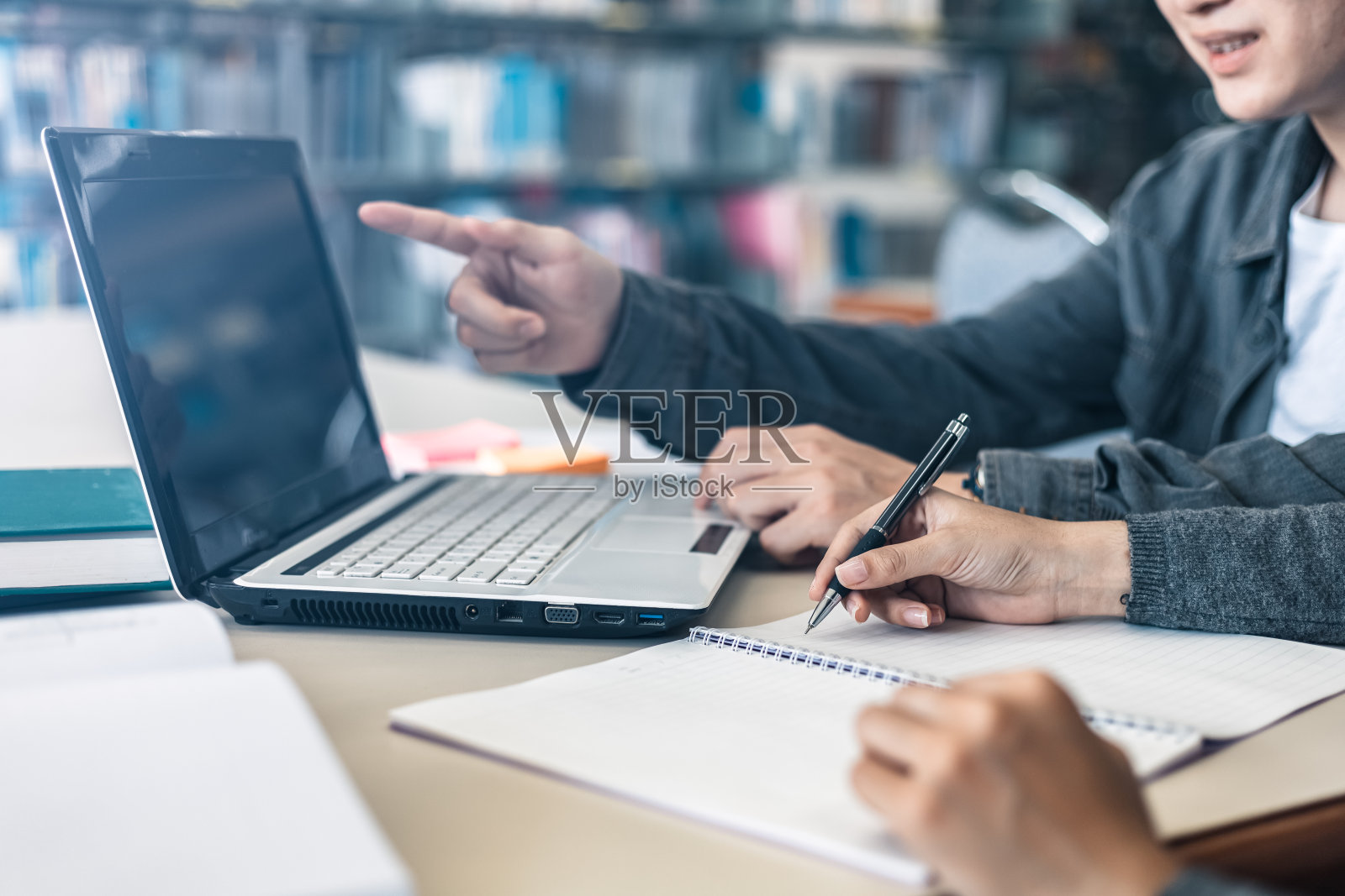 高中生或大学生一起在图书馆学习和写作。学生在图书馆使用笔记本电脑。照片摄影图片