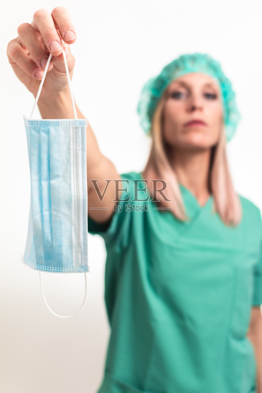 没有对焦的护士,孤立在白色背景中,手拿口罩,在前景中,作为抗议的标志。照片摄影图片