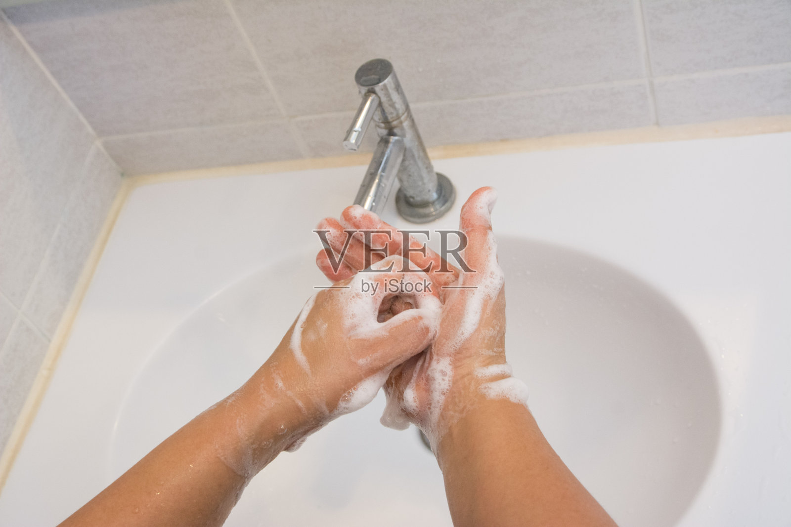 女人在浴室里用肥皂洗手。照片摄影图片