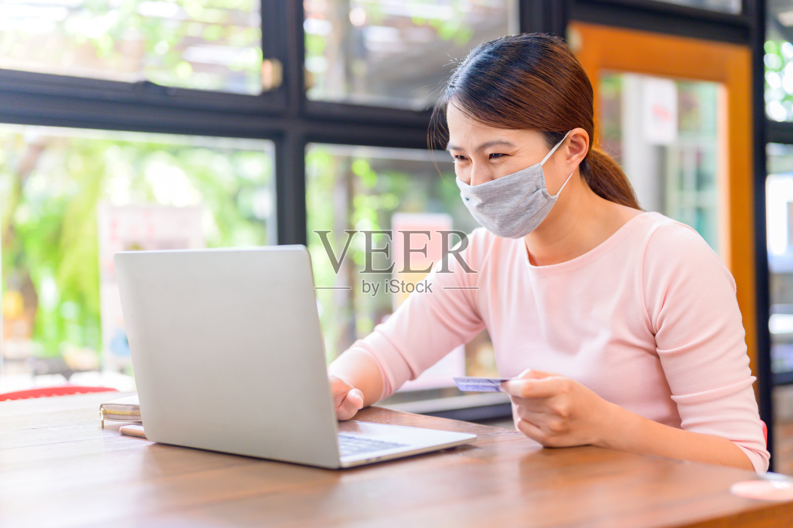 一个用信用卡网购和送货上门的亚洲女人。新冠肺炎后的新常态和新生活。呆在家里,注意安全。社交距离和身体距离。照片摄影图片