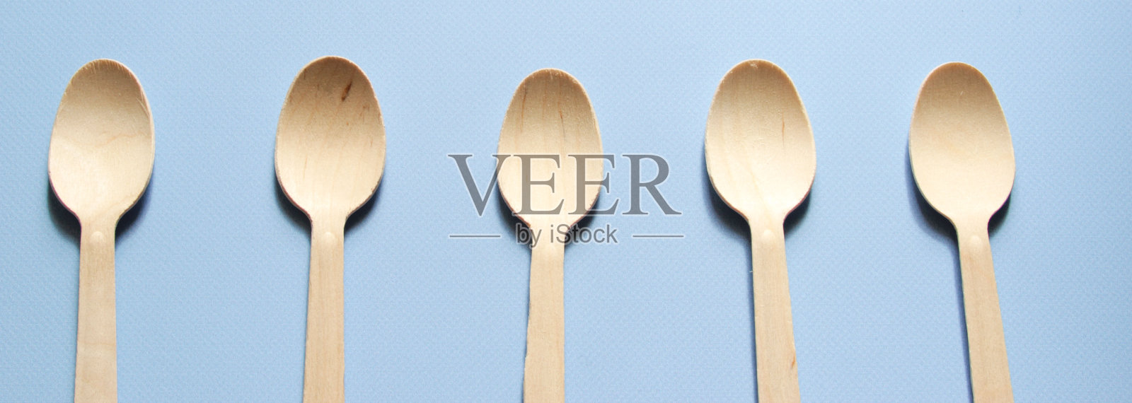 勺子在蓝色的背景上排成一排。环保一次性厨具,由木材制成。32、生态环保,零浪费理念。Flatlay。前视图。照片摄影图片
