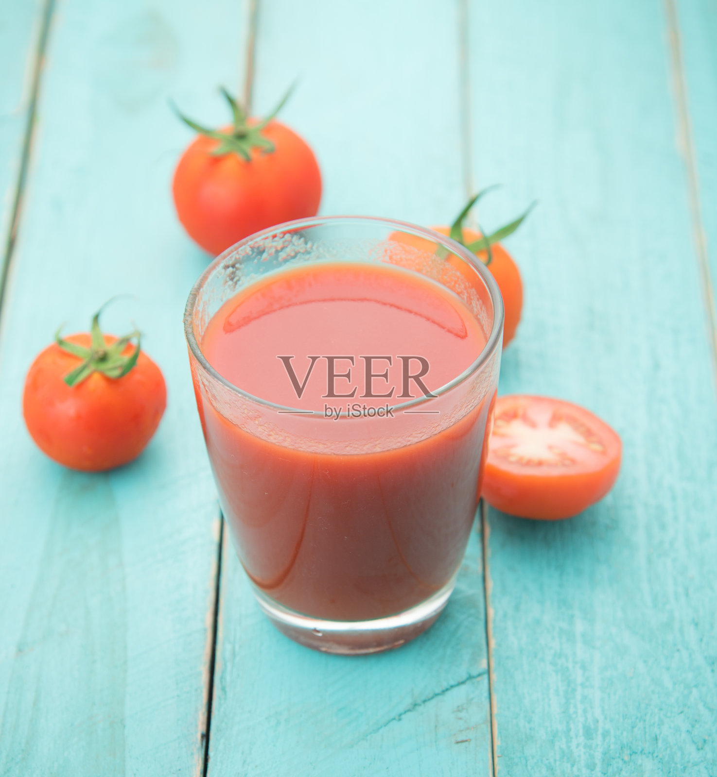 蓝色的木桌上放着一杯番茄汁照片摄影图片
