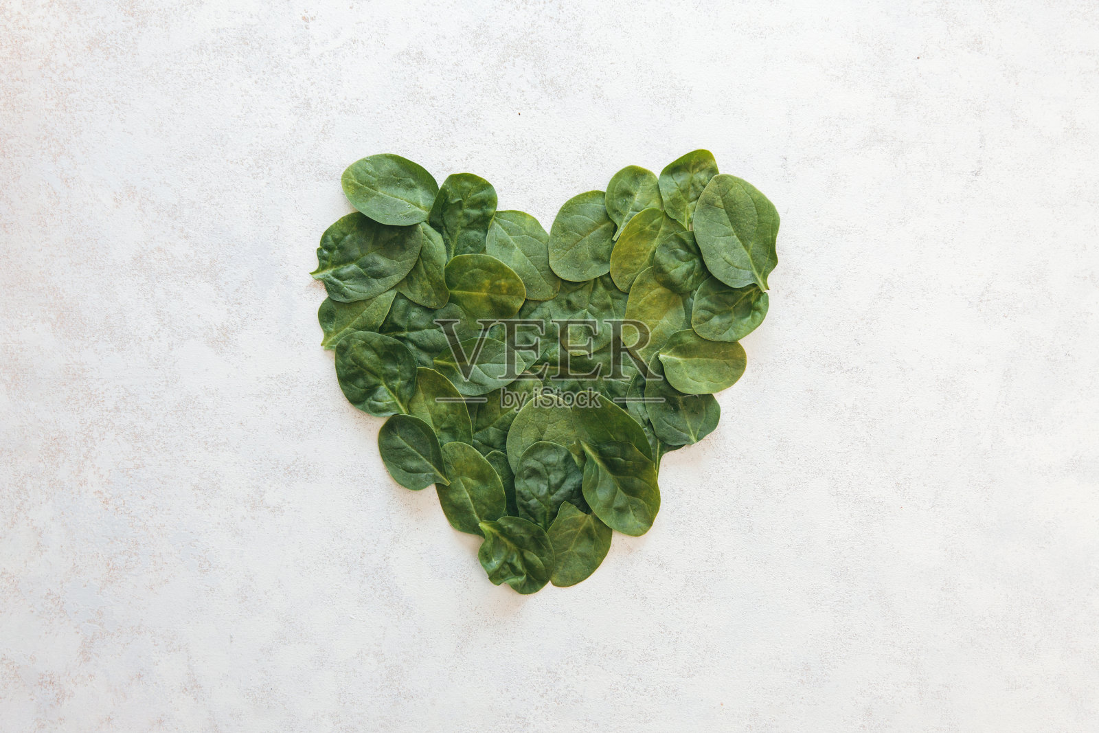 菠菜幼叶在白色背景上呈心形排列。白色背景下的健康心脏概念照片摄影图片