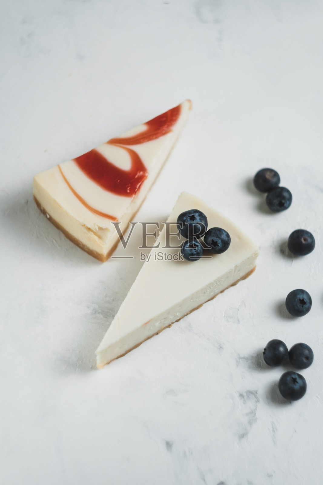 桌上有蓝莓和草莓芝士蛋糕。照片摄影图片