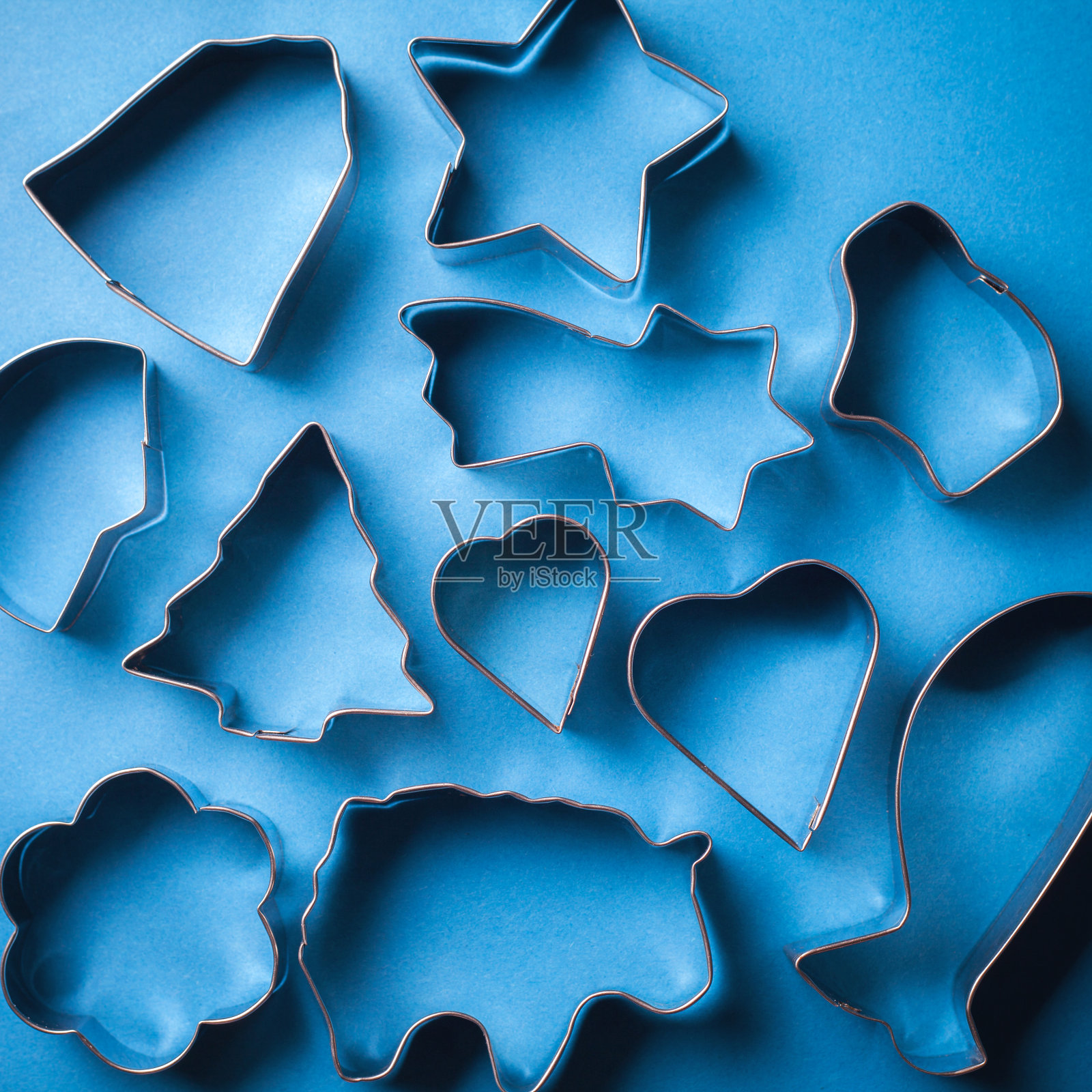 蓝色背景上制作饼干的金属模具。制作装饰甜点的节日形状的糕点模具。照片摄影图片