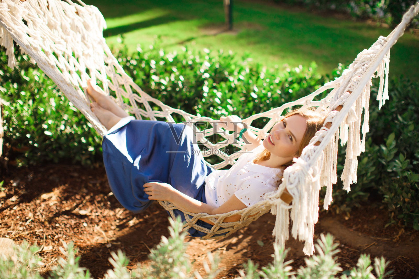 一个穿着蓝裙子的女人躺在公园的吊床上照片摄影图片