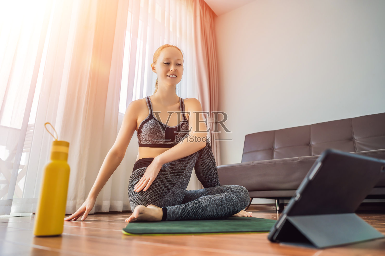 健身女性在家里的地板上锻炼,在平板电脑上看健身视频。人们上网运动是因为冠状病毒照片摄影图片