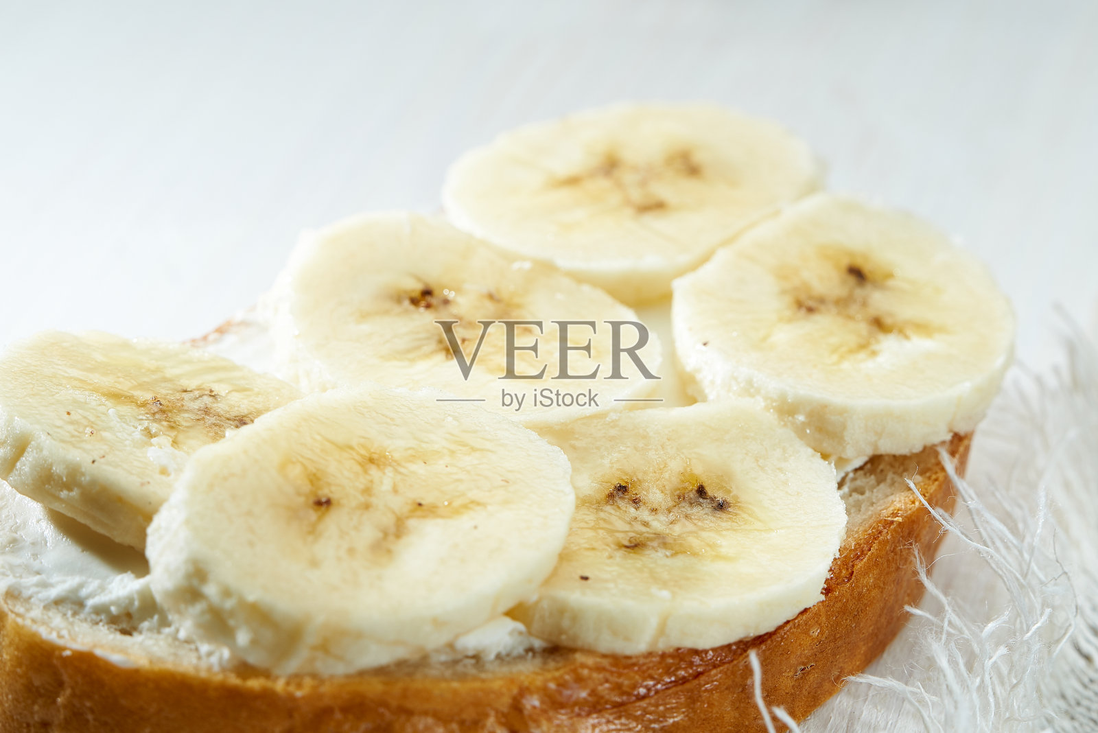 白色木桌上放着香蕉片三明治。照片摄影图片