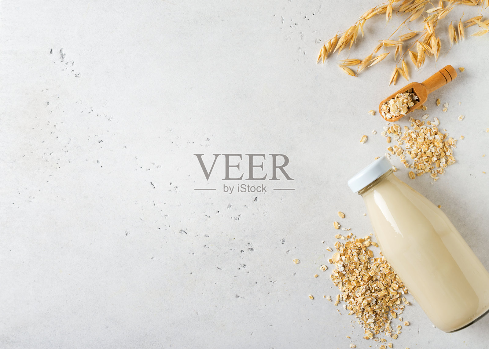 玻璃瓶装的燕麦牛奶,白色背景上有薄片和穗状或穗状的谷粒照片摄影图片