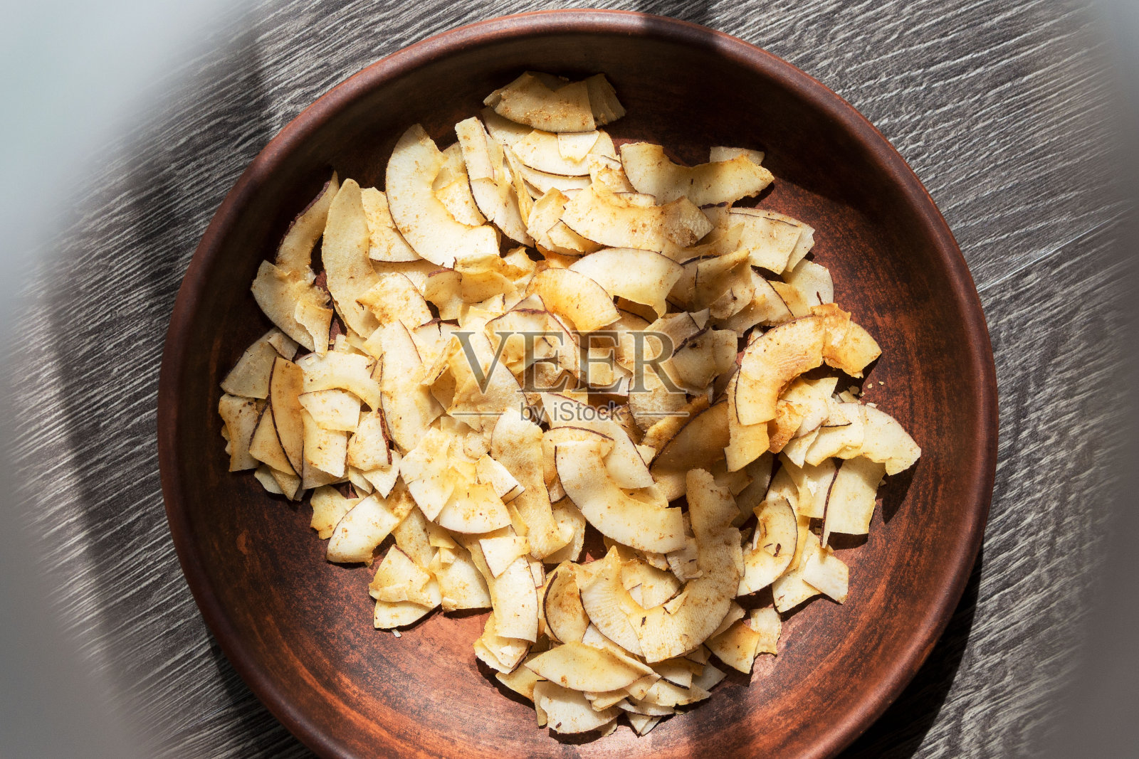 美味酥脆的椰子片与咸焦糖在棕色陶瓷盘子。椰子果肉制成的天然产品。照片摄影图片