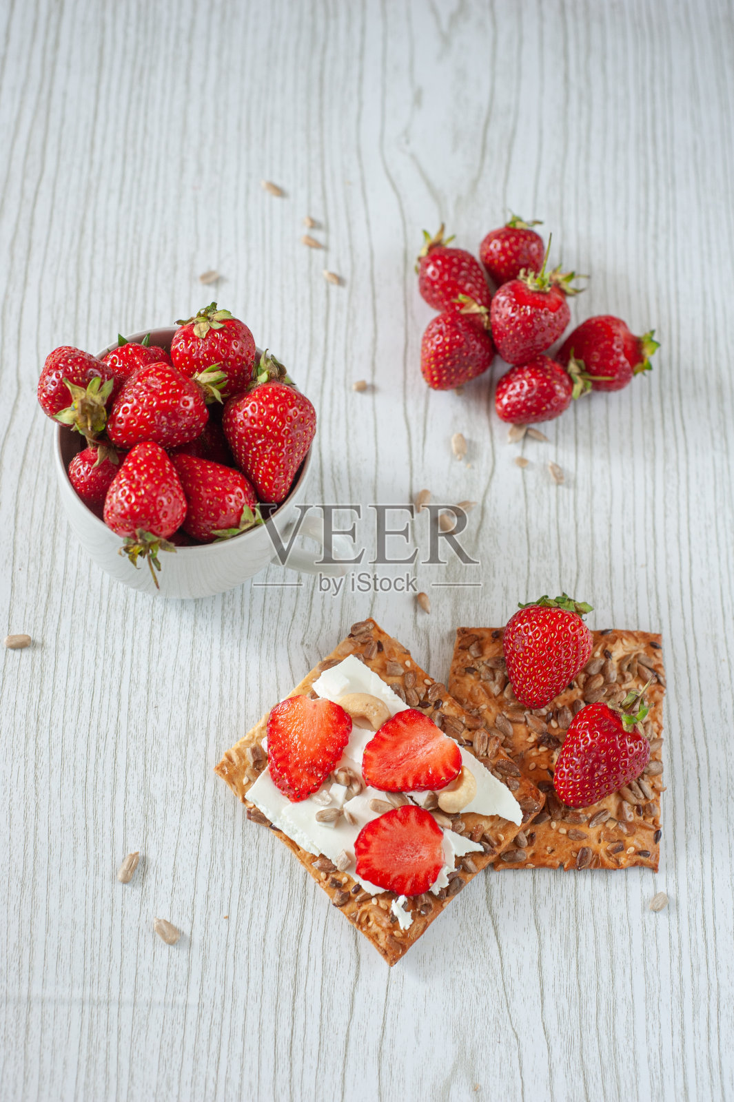 杯子里的草莓放在一个浅色的木制背景上。奶酪、草莓和榛子饼干。膳食营养。夏天早餐。一个健康的零食。照片摄影图片