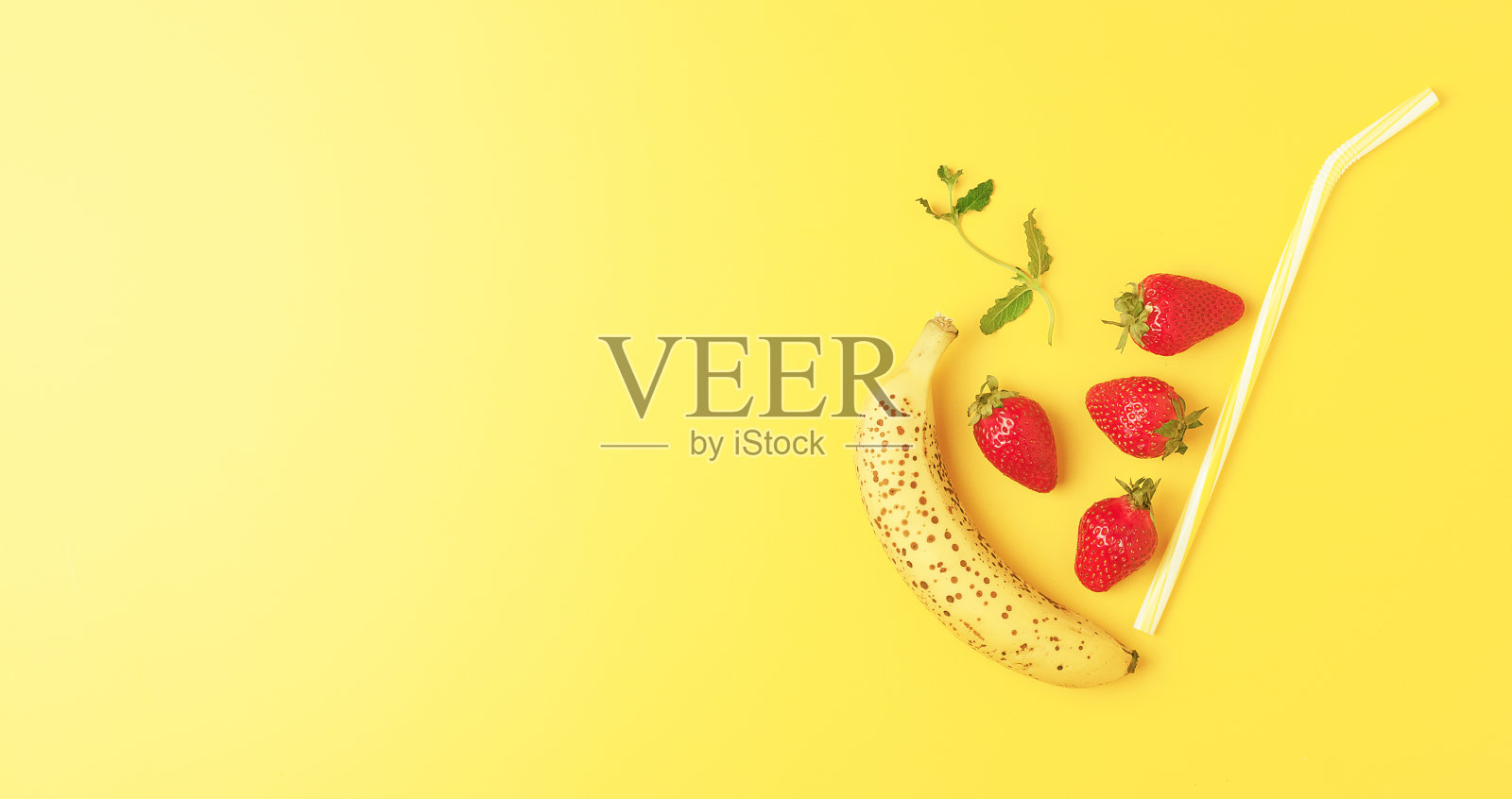 香蕉草莓冰沙装饰薄荷在黄色的背景。五彩缤纷的夏季食物。创意健康饮食理念。平铺,拷贝空间照片摄影图片