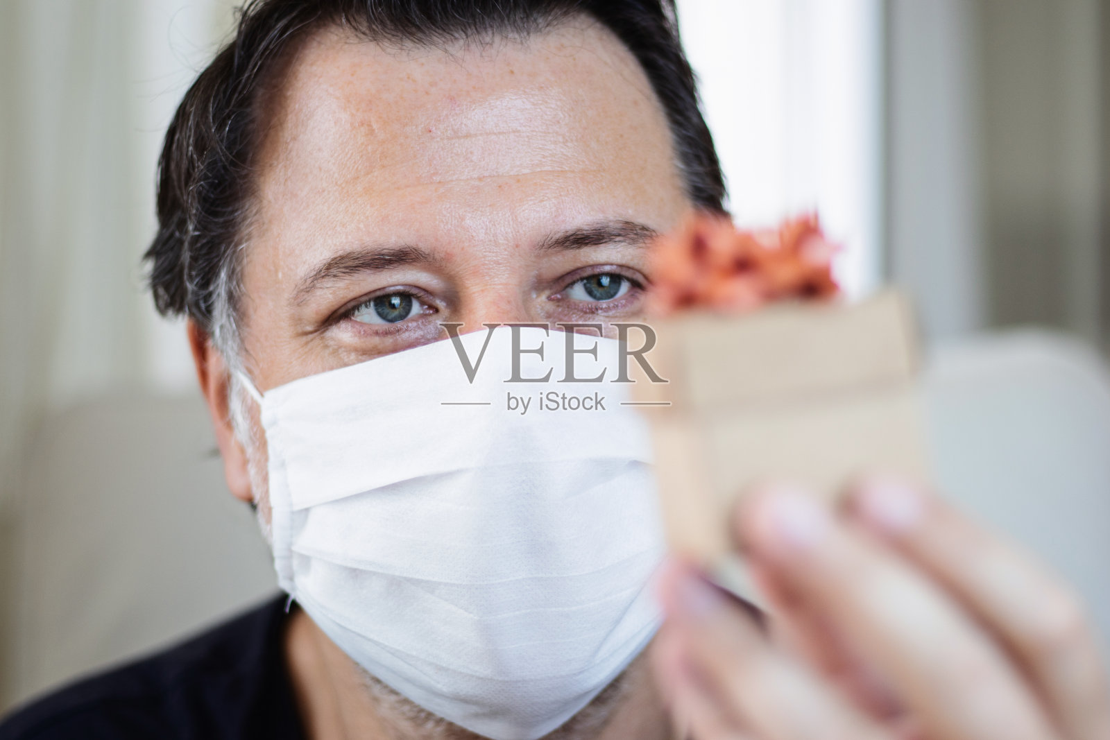 那个戴着面具的人手里拿着一个礼品盒。父亲节的概念。照片摄影图片