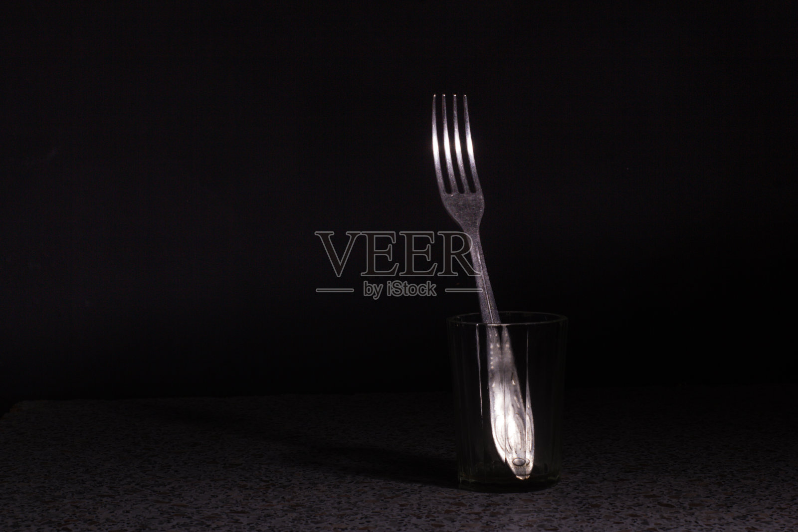 叉子放在杯子里,背景是黑色。摄影工作室照片摄影图片