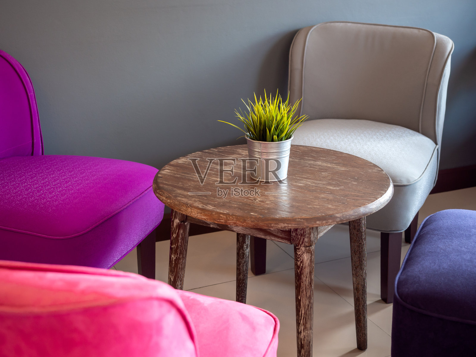 绿色的叶子在锌锅在圆木桌和多色舒适的沙发咖啡馆。照片摄影图片