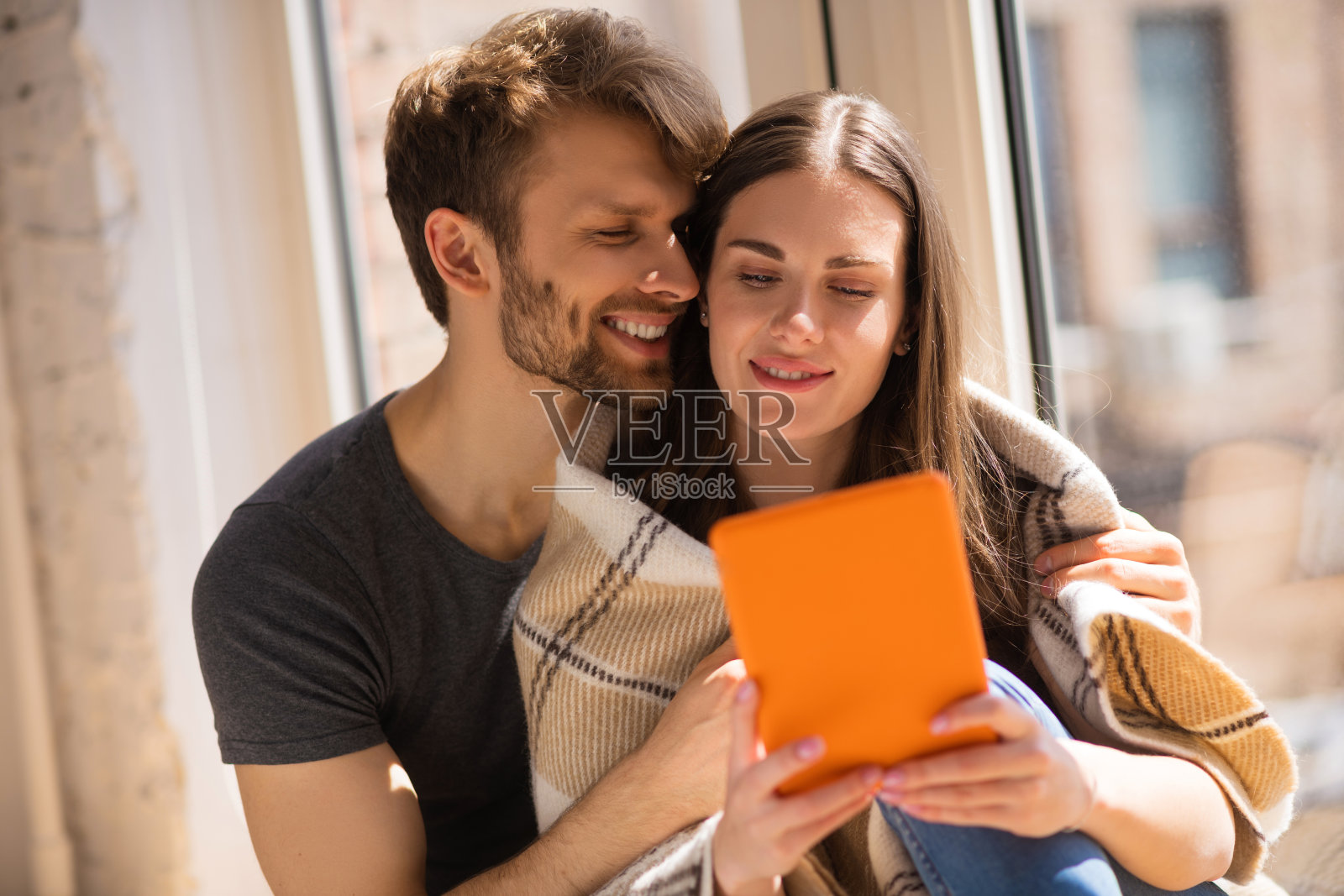 年轻的胡子男子拥抱他的妻子,而她看视频照片摄影图片