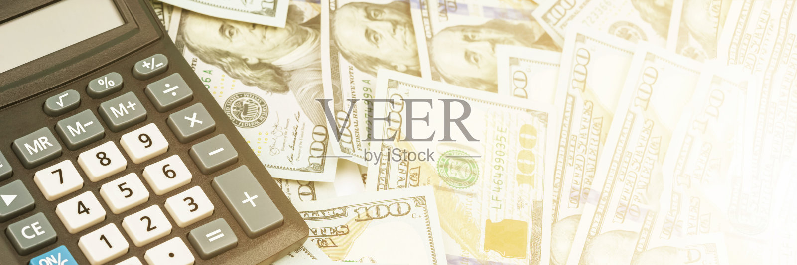 灰色和白色按钮的计算器躺在美元堆上照片摄影图片