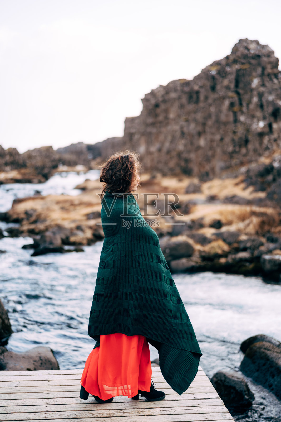 一名身穿红色连衣裙的女孩在萨德兰地区廷韦德尔国家公园伊萨罗河伊萨罗福斯瀑布附近。照片摄影图片