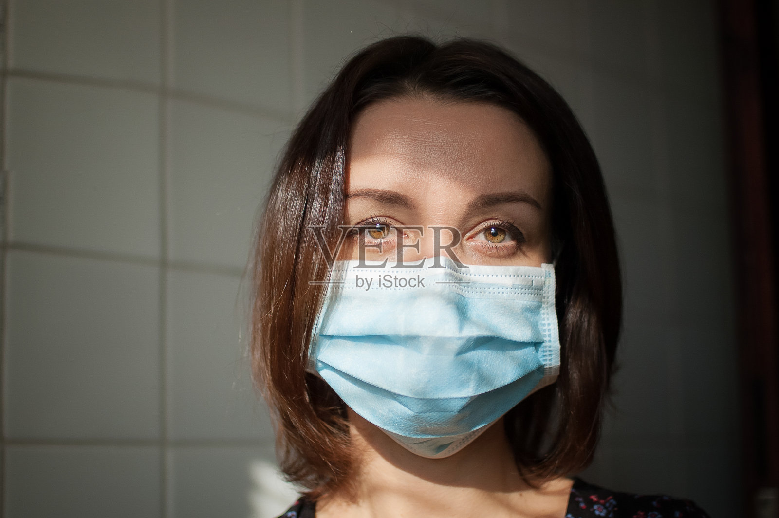 冠状病毒Covid-19暴发。在大流行期间,年轻妇女戴着外科口罩在家隔离,以防止感染病毒照片摄影图片