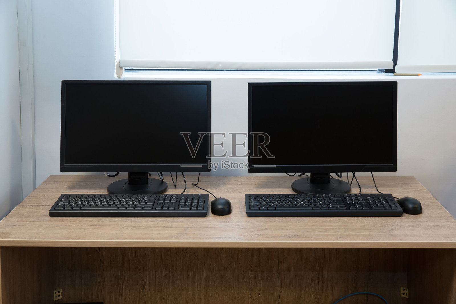 两台电脑和一张桌子。键盘和鼠标。桌子上有两个黑屏的电脑显示器。照片摄影图片