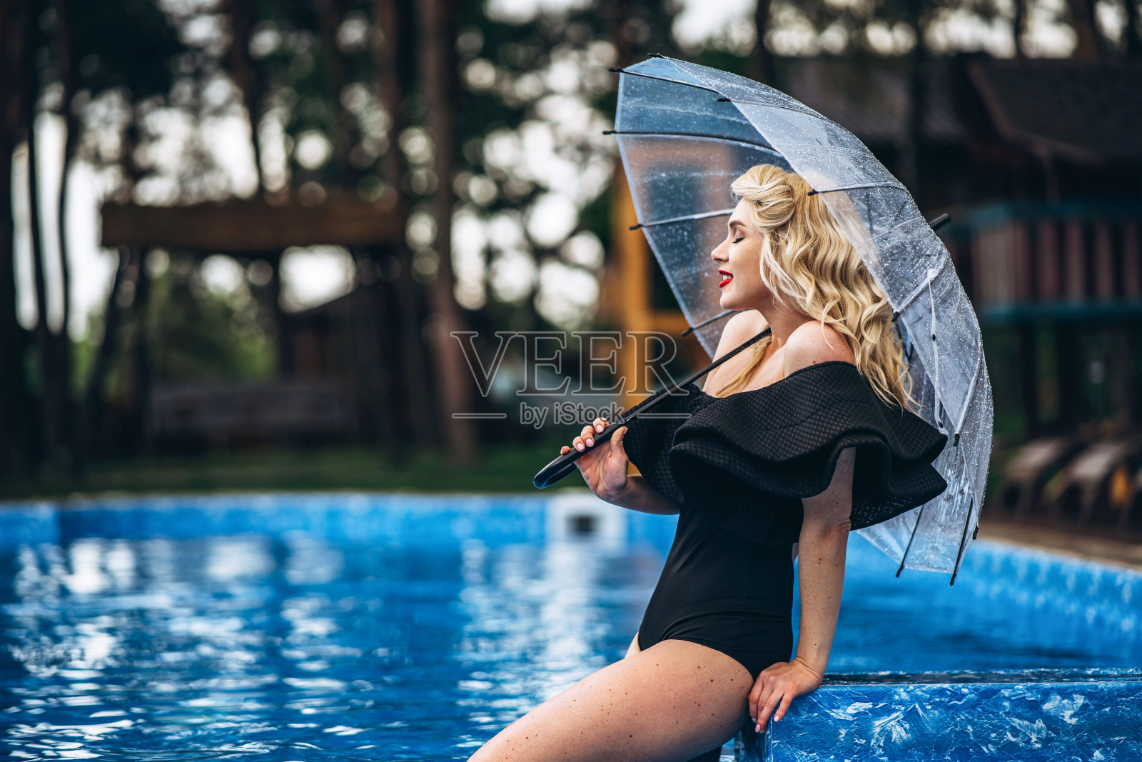 漂亮的别针风格的金发在黑色复古泳衣放松在游泳池照片摄影图片