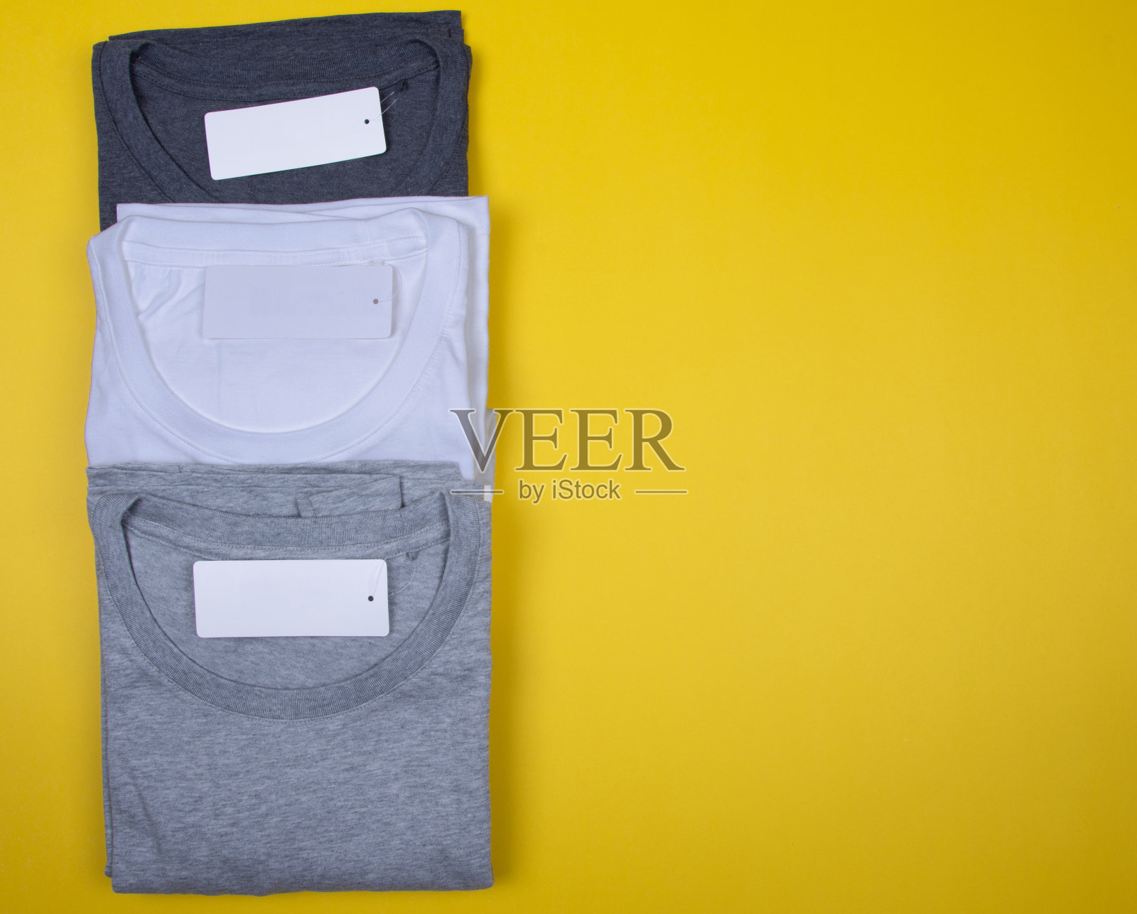 深灰色,灰色和白色t恤上的亮黄色背景。照片摄影图片