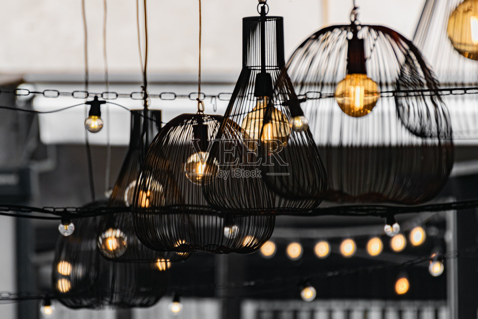 咖啡馆在露天的人行道上用黄色的灯泡装饰。现代室内的仿古灯光装饰。照片摄影图片