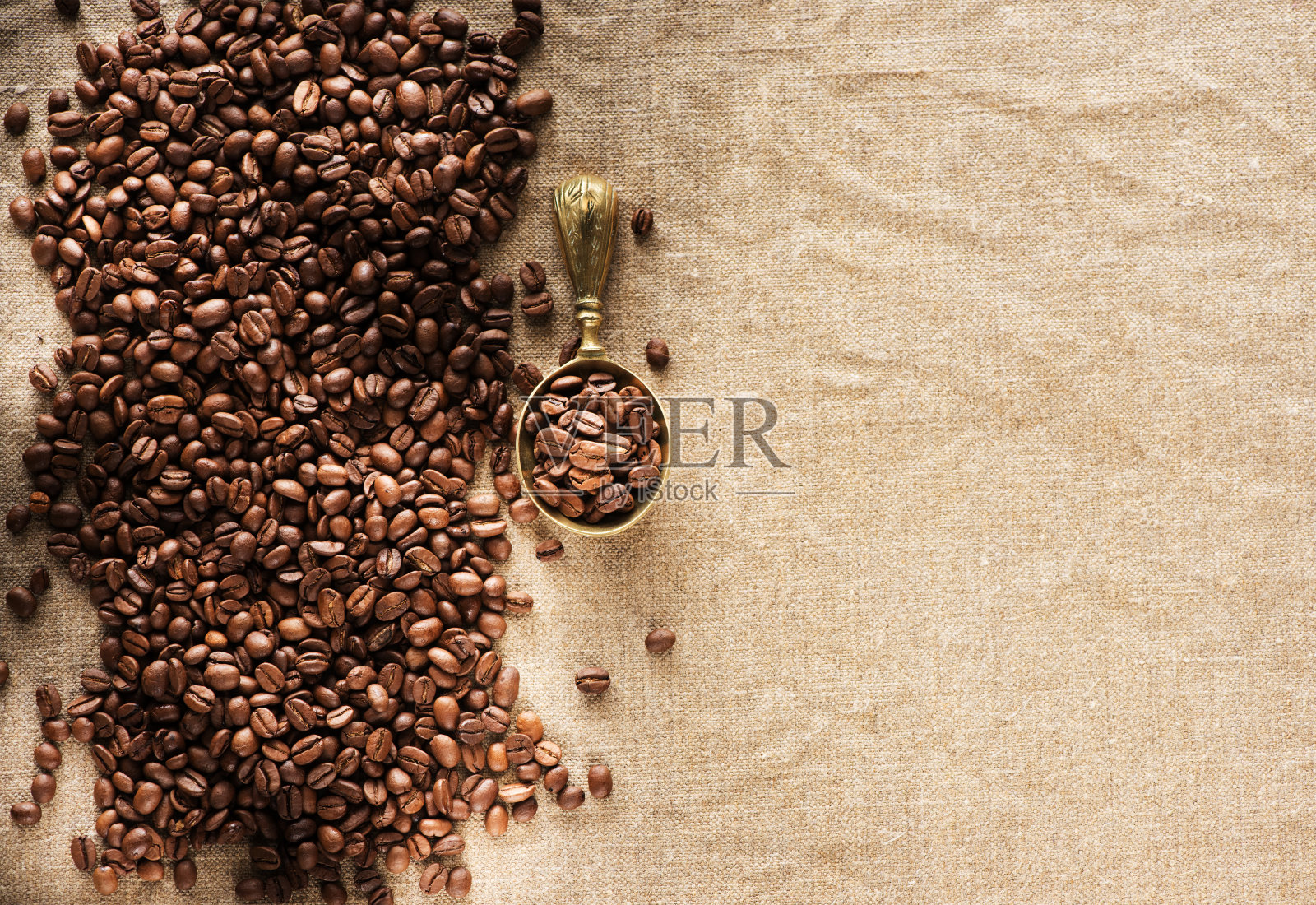 粗麻袋上放着咖啡豆和勺子,俯视图。咖啡的背景照片摄影图片