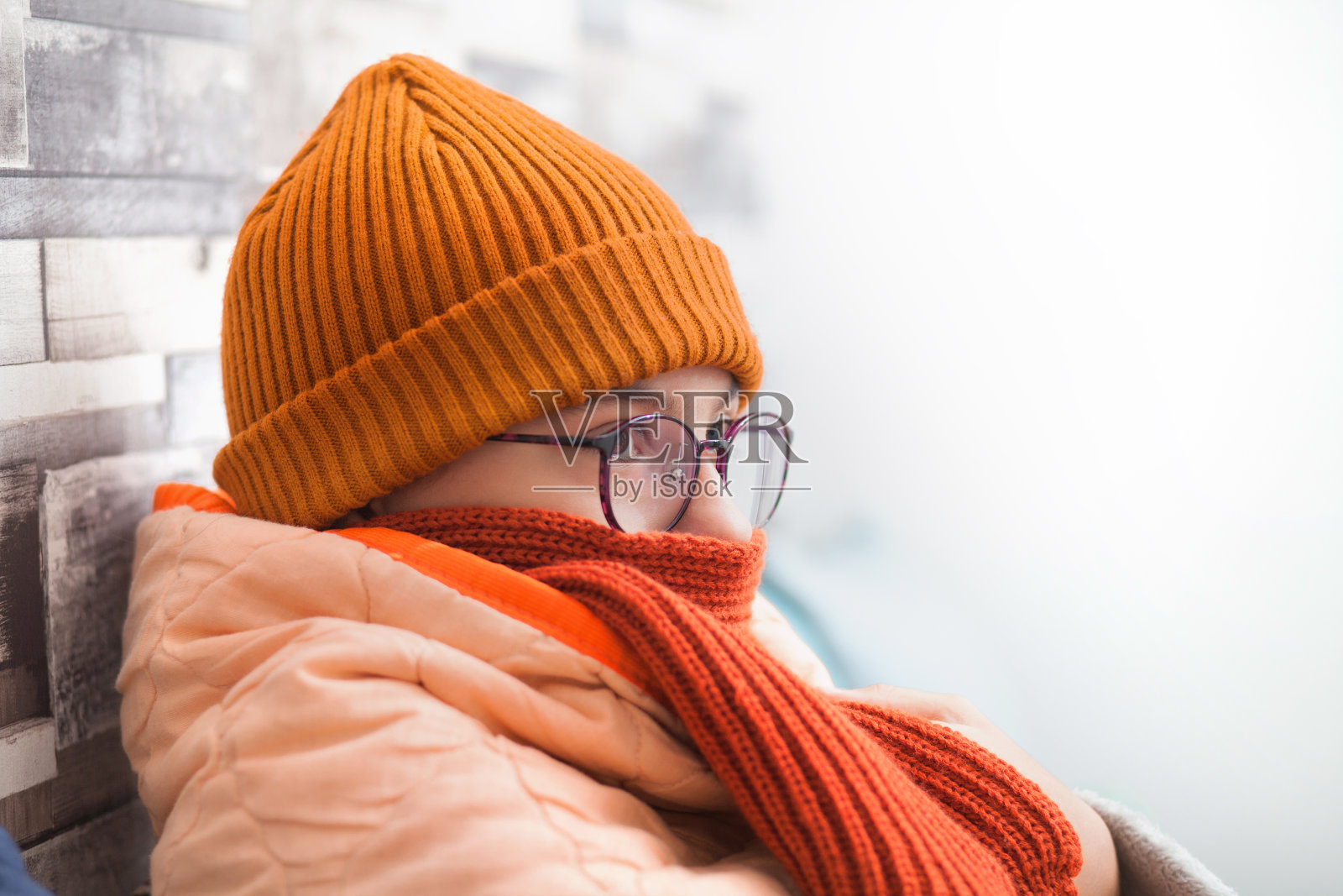 一个生病的少女裹着毯子坐在沙发上。照片摄影图片
