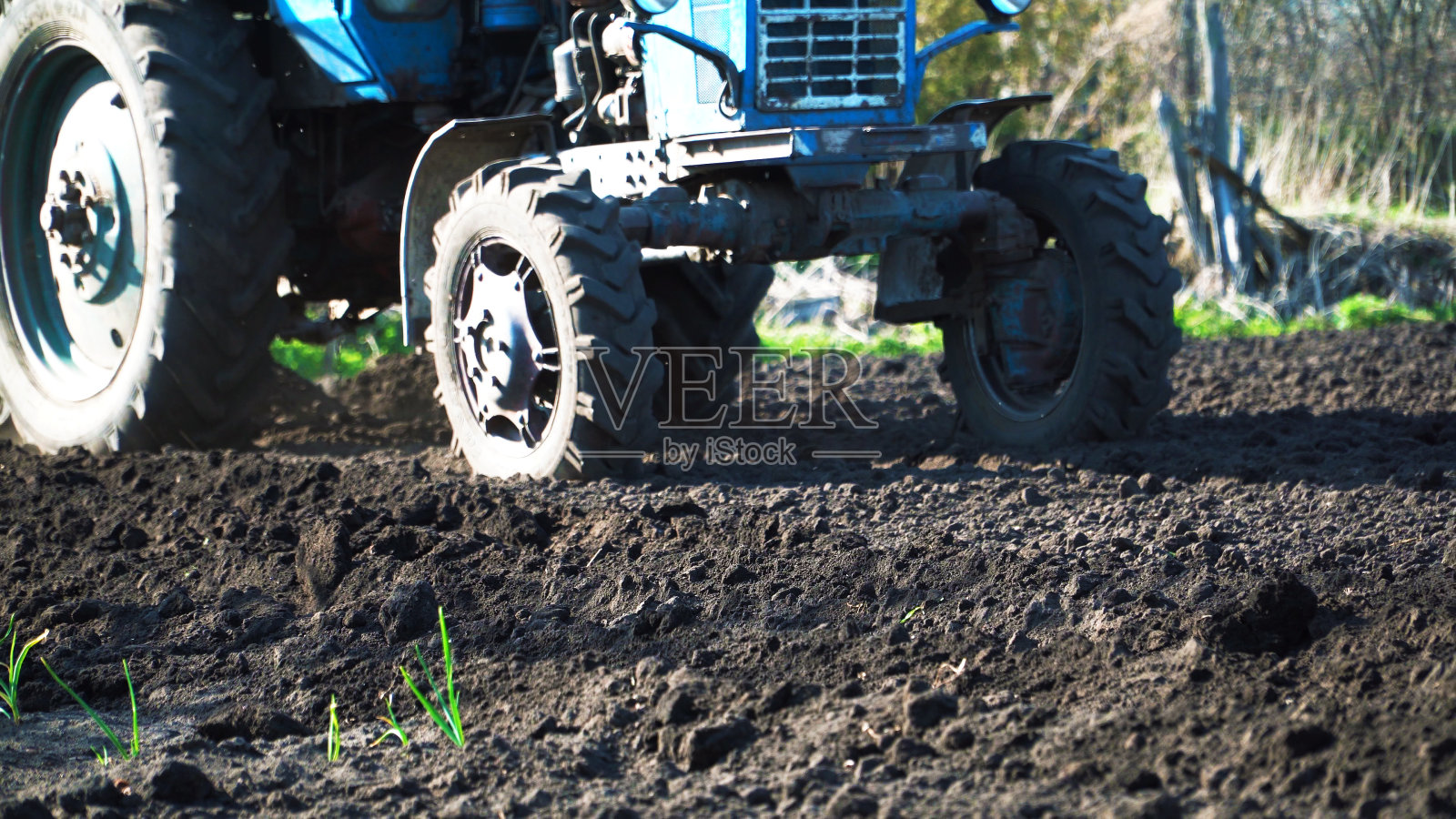 拖拉机在田里犁沟。拖拉机在村里的黑土地里干活照片摄影图片