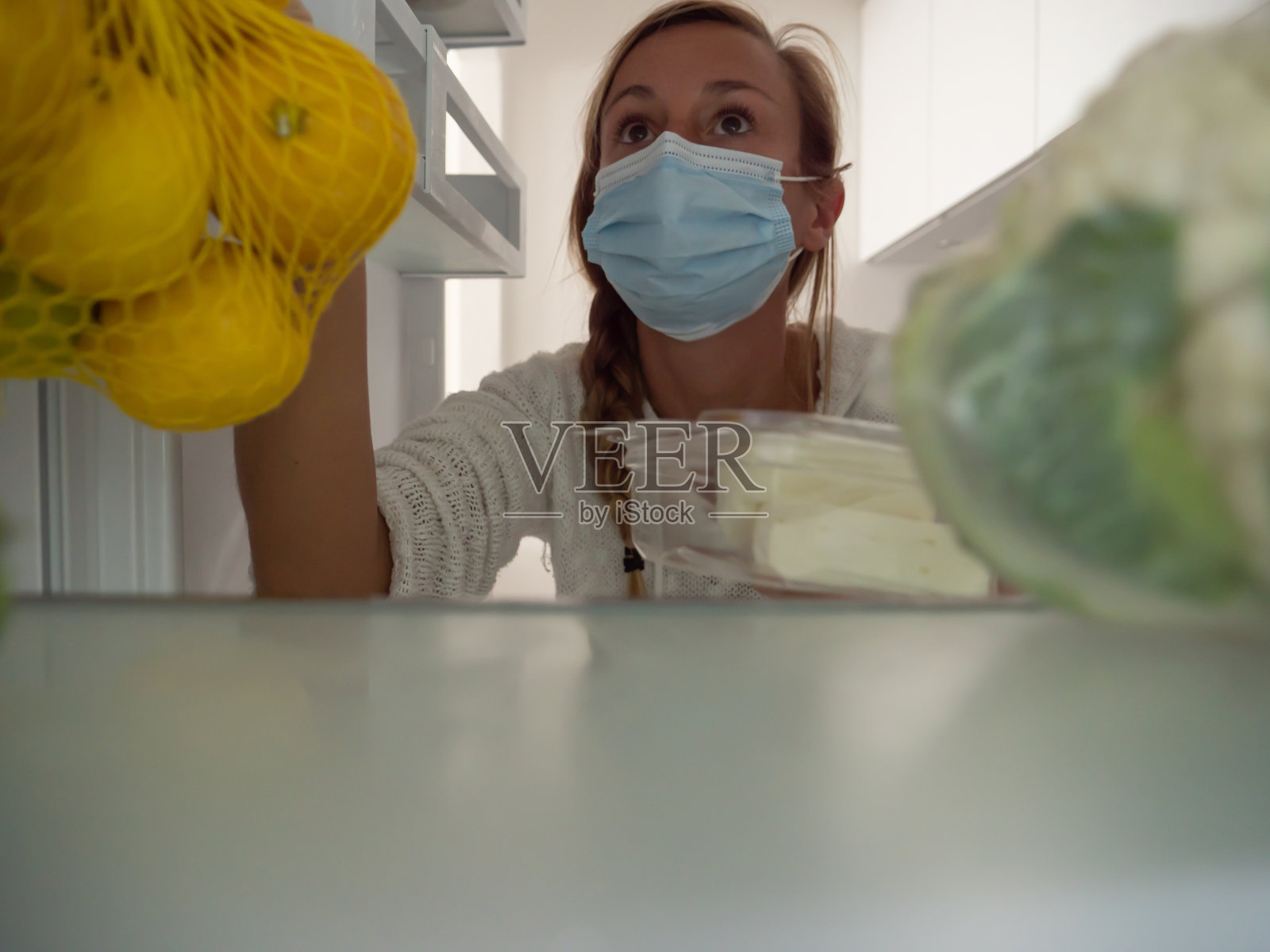 一名年轻女子将食品杂货放进冰箱照片摄影图片