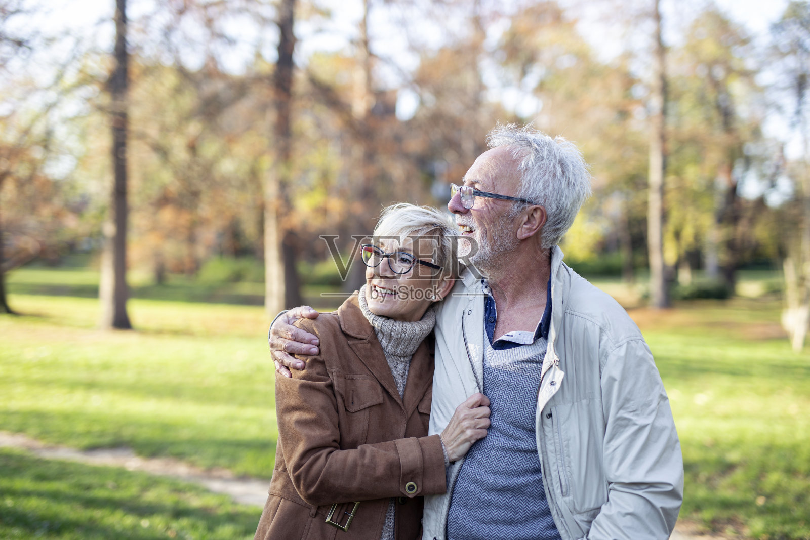 在阳光明媚的日子里,一对成熟的夫妇在公园里散步,面带微笑照片摄影图片