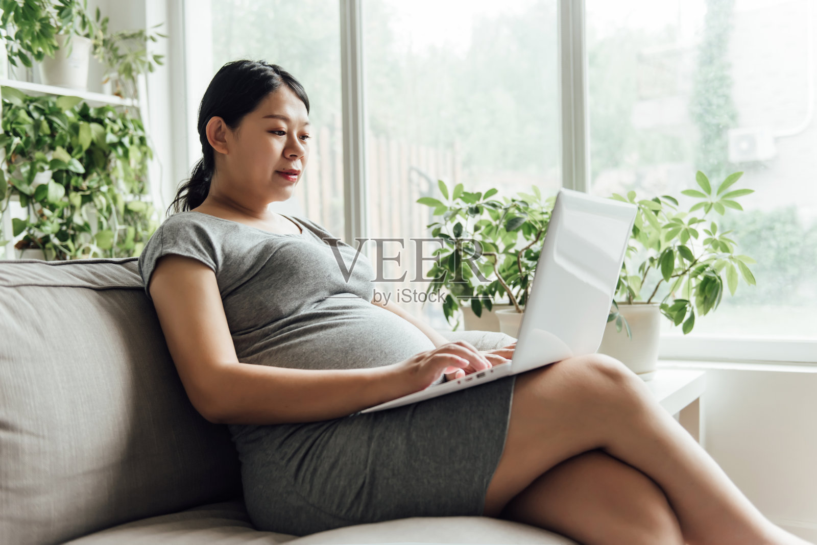 一名年轻的亚洲孕妇正在使用电子设备照片摄影图片