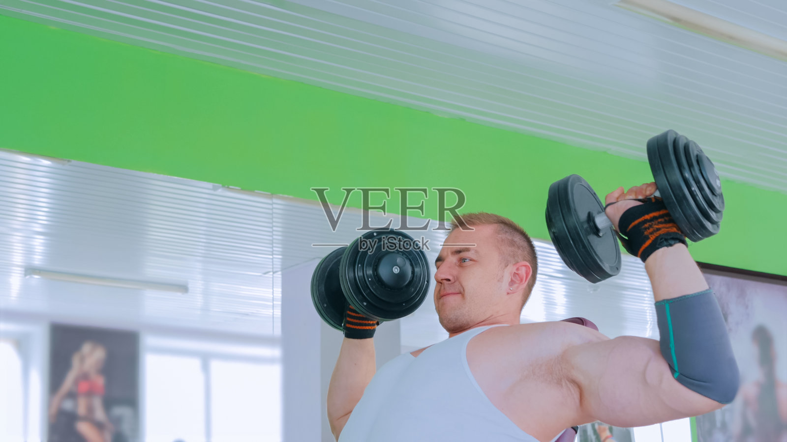 健壮的年轻人在健身房举哑铃照片摄影图片