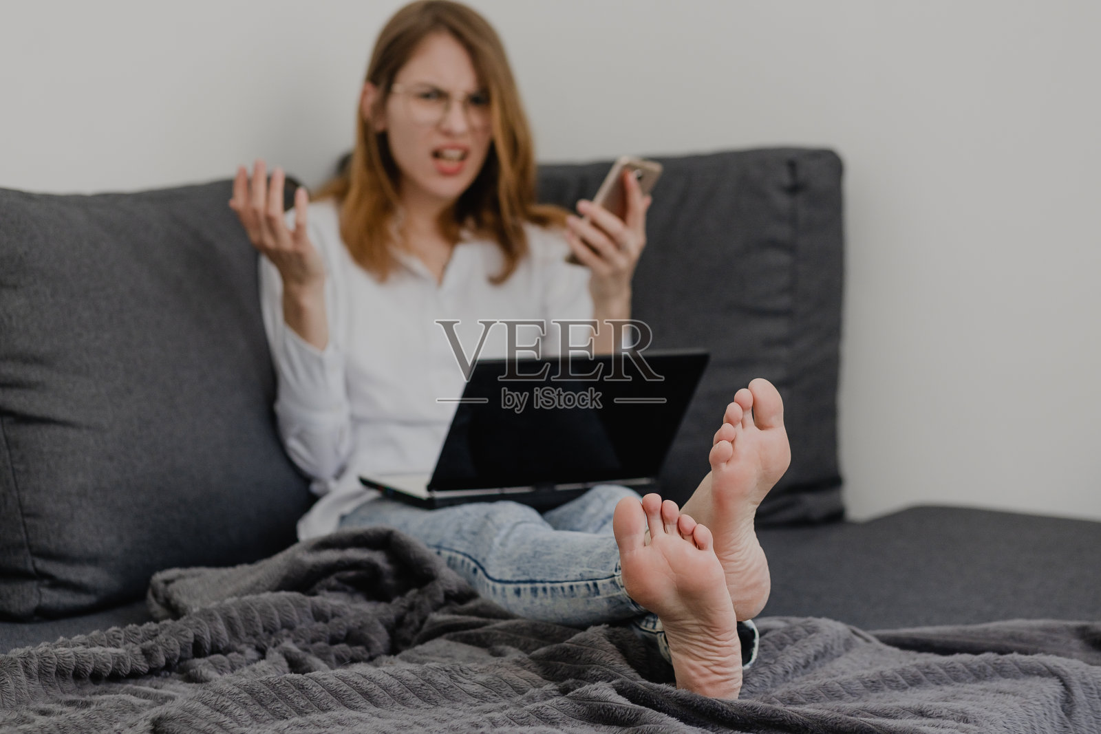 迷人的年轻女人在家工作-女企业家坐在沙发上笔记本电脑和检查手机从舒适的家照片摄影图片