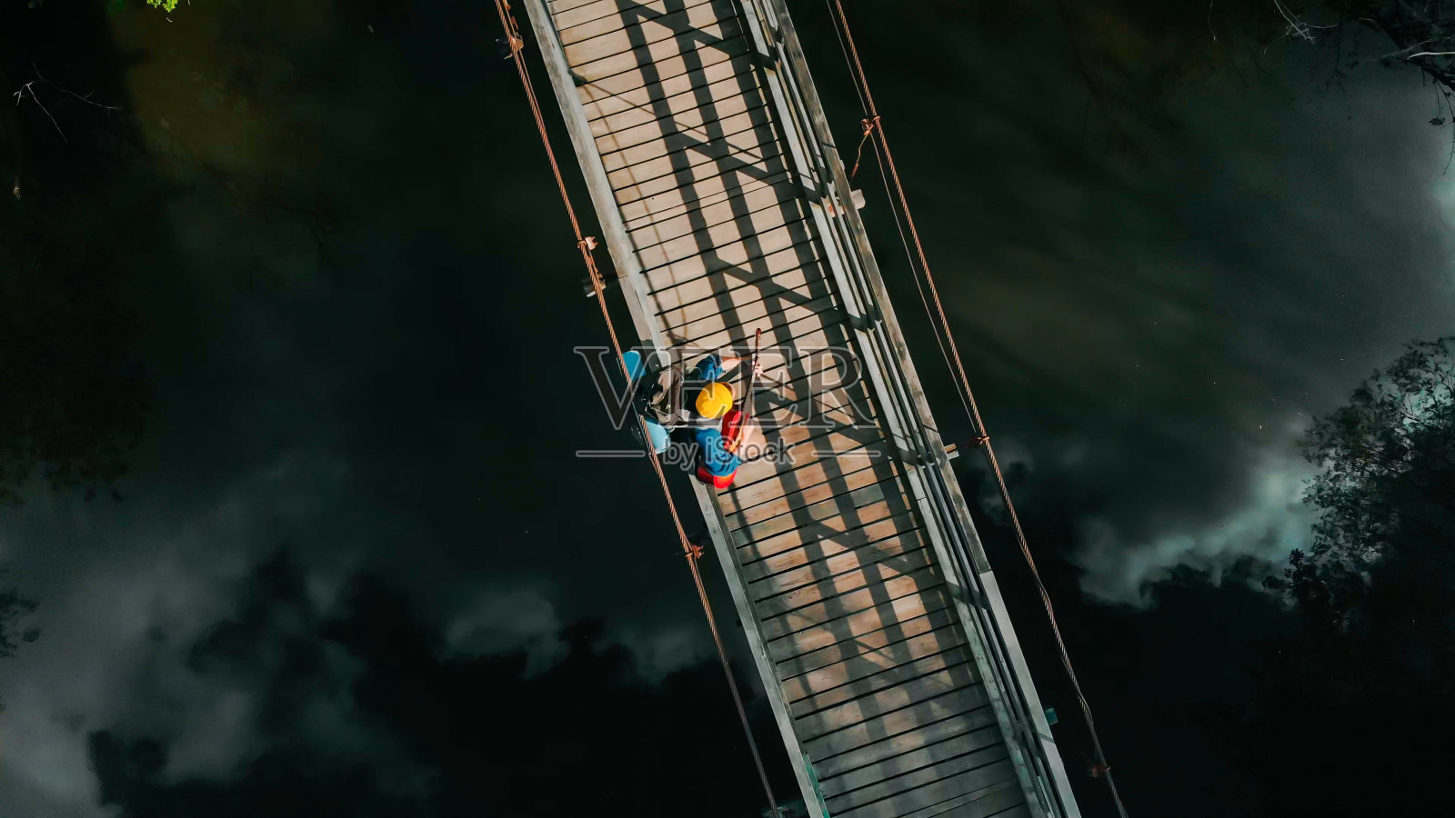 一个年轻人在水上的索桥上弹吉他照片摄影图片