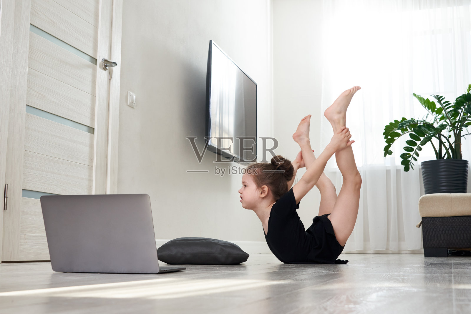 小女孩在家做体操练习,用笔记本电脑在线学习,网络教育理念照片摄影图片