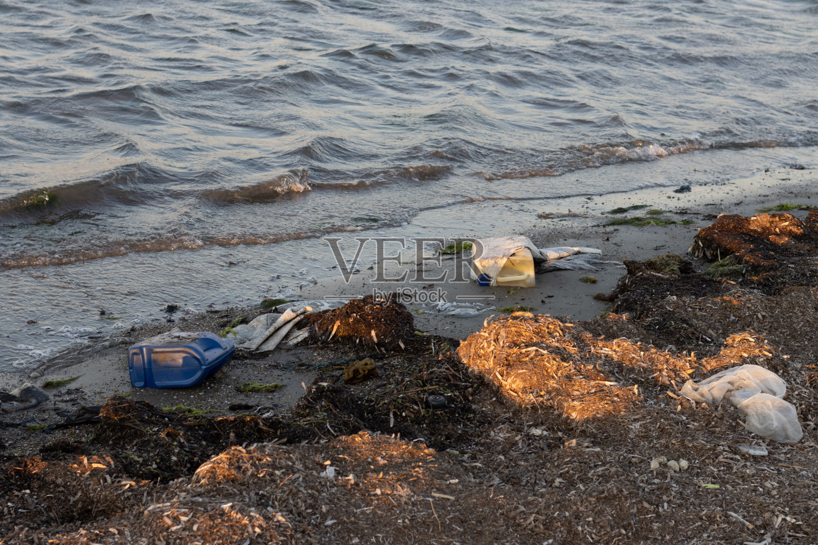 塑料瓶和各种垃圾堆放在肮脏的沙滩上照片摄影图片