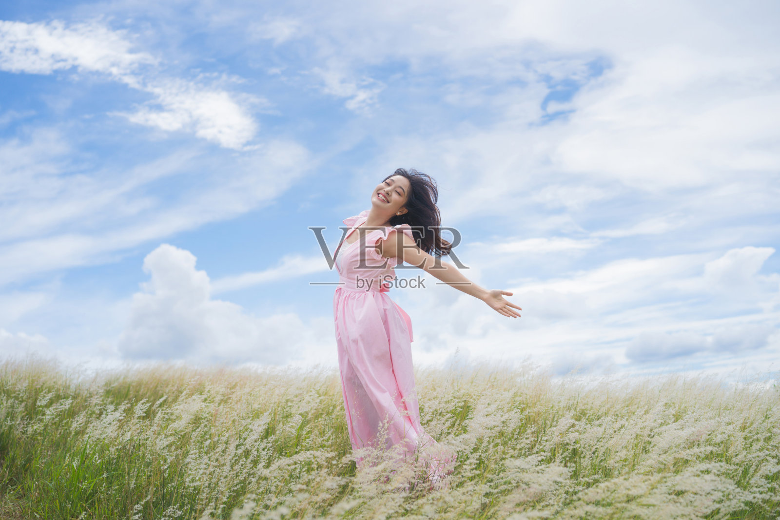 美丽的亚洲女人她拥有自由。她在草地上跳。照片摄影图片