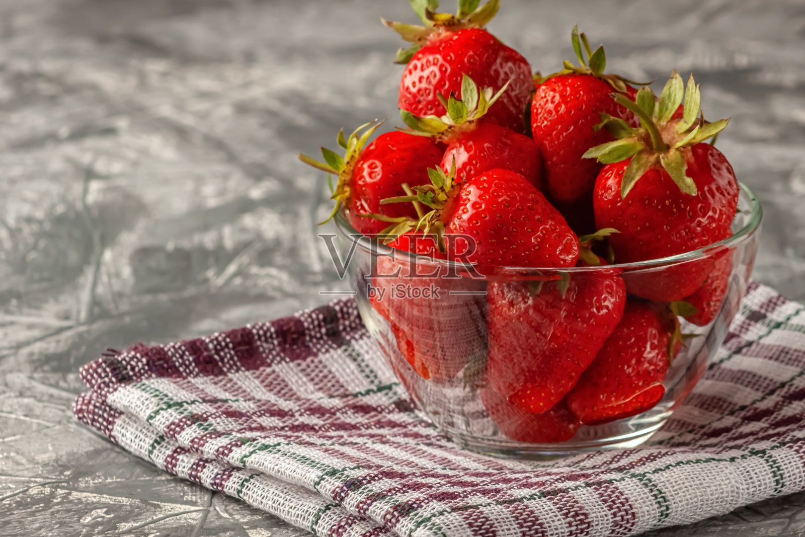 新鲜、成熟和美味的草莓在一个玻璃碗在灰色的背景照片摄影图片