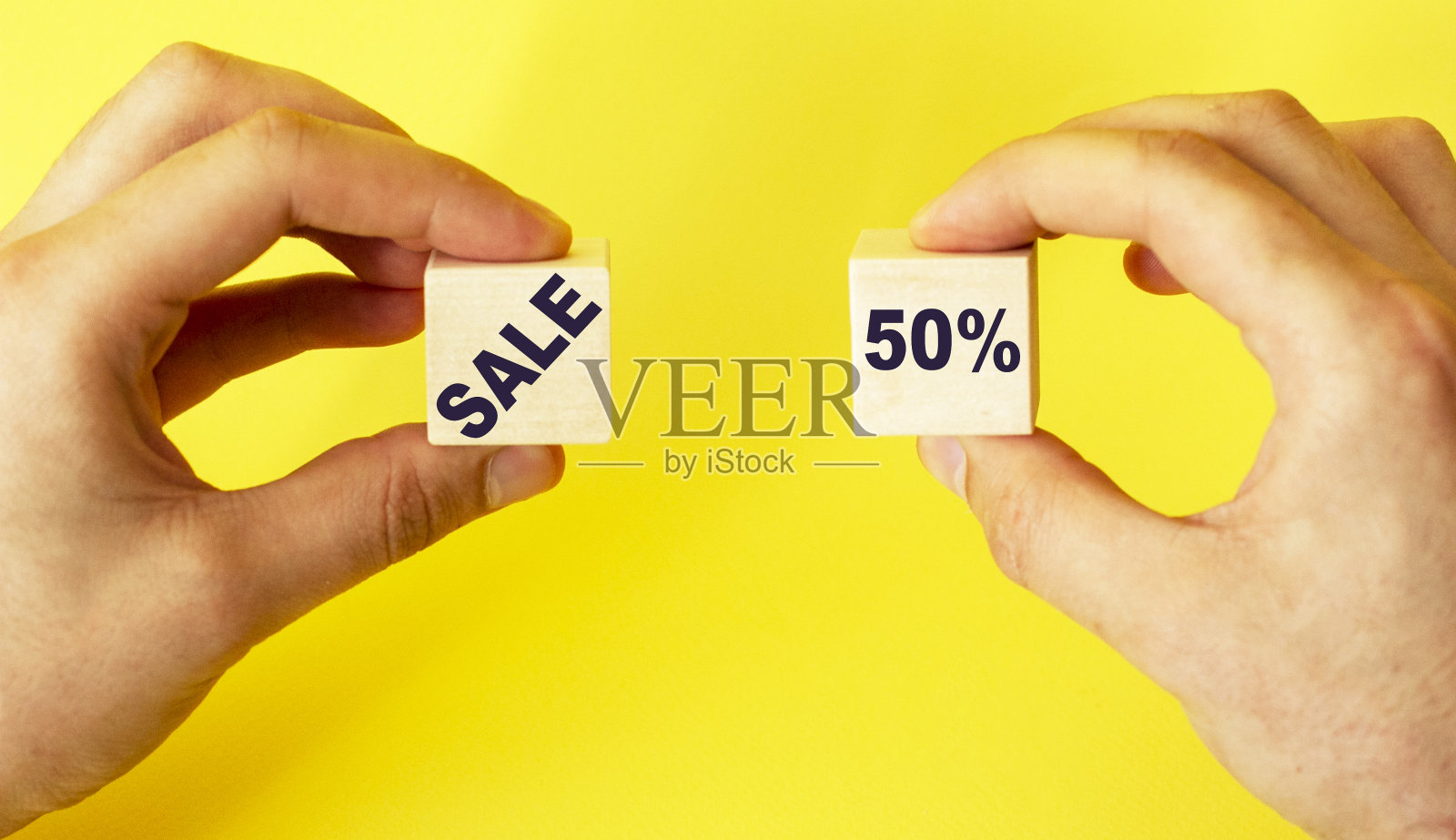 一个男人拿着黄色背景上有50个文字的立方体照片摄影图片