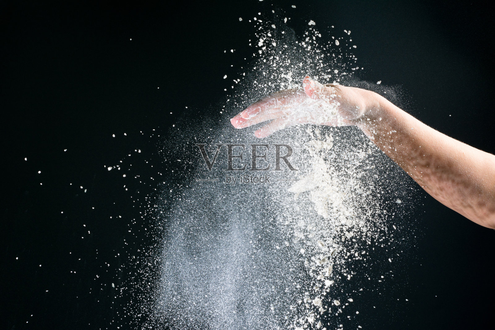 孤立的黑色背景上,女性的手倒着白面粉像雪一样烘烤照片摄影图片