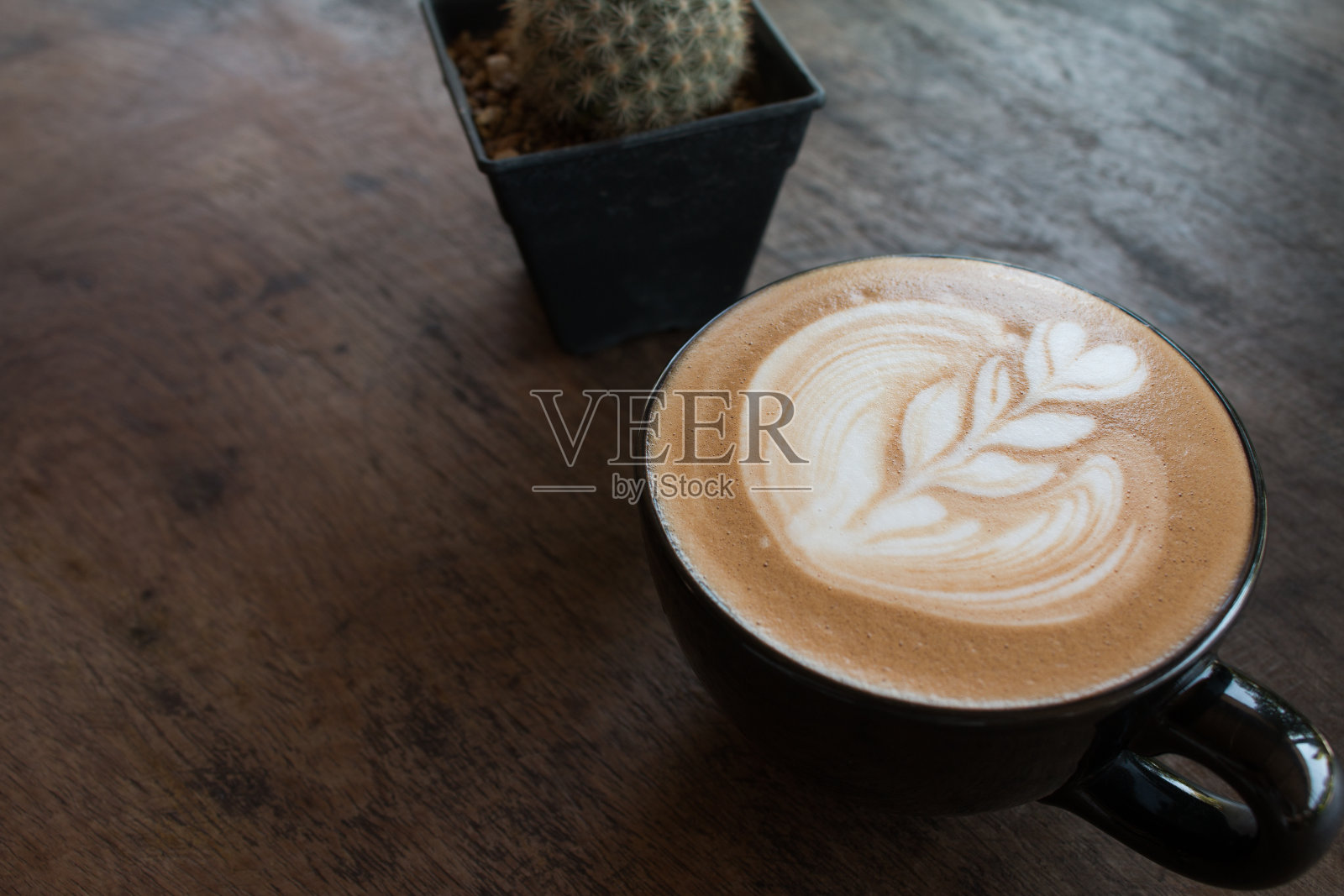 近距离的杯热拿铁艺术咖啡在木桌上。照片摄影图片