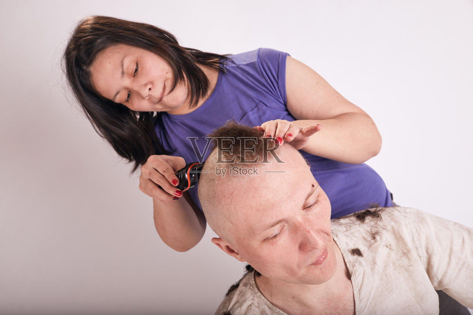 新冠肺炎隔离期间,女性在家为男性理发。自我隔离家庭生活方式照片摄影图片