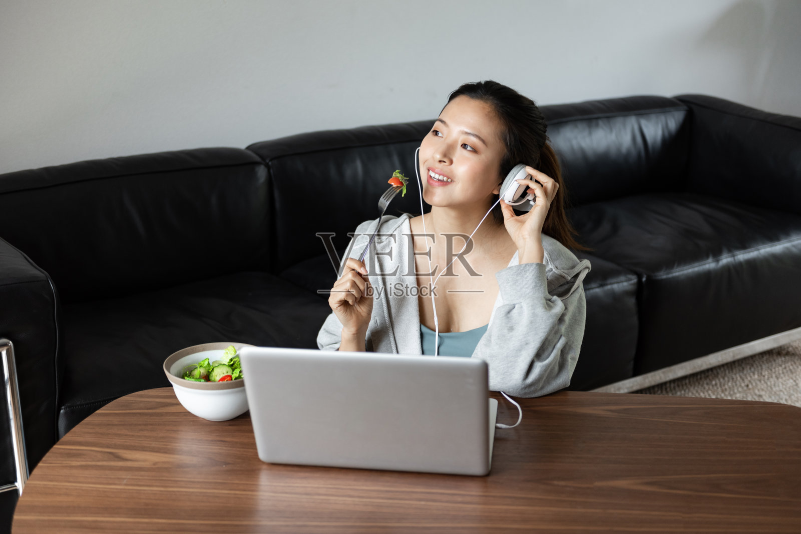 一位年轻的亚洲妇女在客厅里使用电脑照片摄影图片