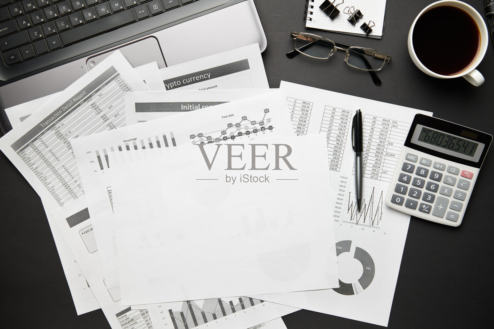 俯视图的现代黑色办公桌上有笔记本电脑,笔记本,铅笔,财务报告和很多东西。平铺表布局。照片摄影图片